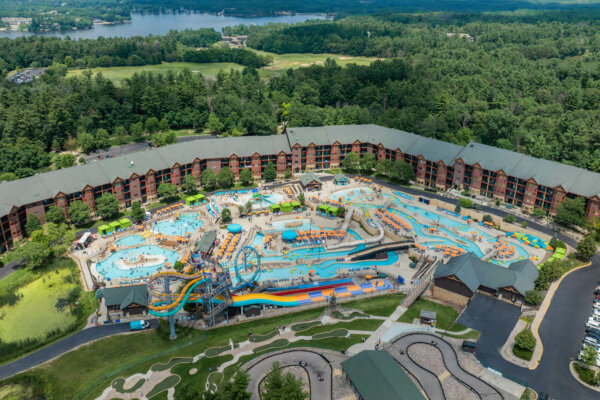 Lost World drone gallery image showing hotel, slides, mini golf, go-cart track and lazy river outdoor wide angle shot at Glacier Canyon Wilderness Resort. Part of Wild Rock golf course can be seen in distance along with Lake Delton.