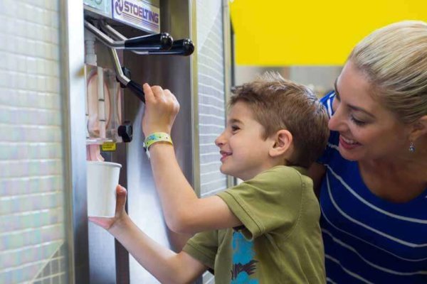 mom and son pouring frozen yogurt at yukon yogurt