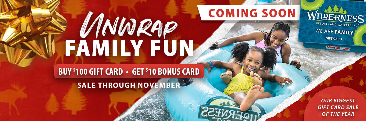 Promotional graphic for Wilderness Resorts gift card sale coming in November. Text: ‘Unwrap Family Fun. Buy $100, get $10 bonus. Sale through November.’ Two children ride a water slide with a gold bow and red holiday background. Gift card in corner reads ‘We Are Family.