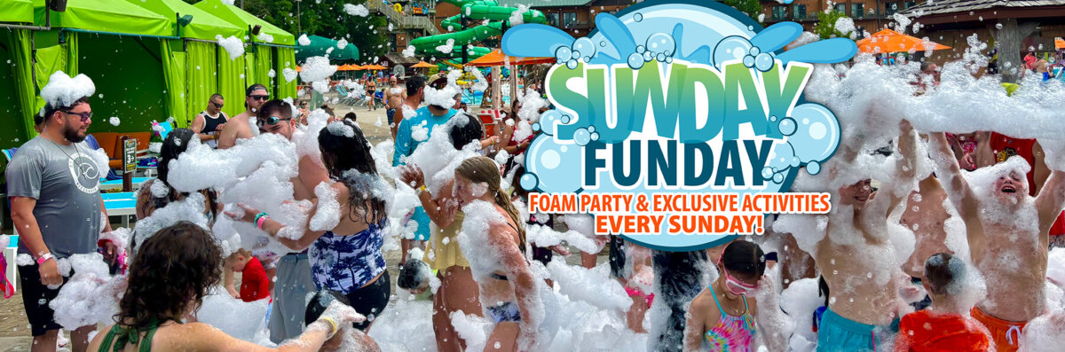 Guests of all ages enjoy a foam party at an outdoor waterpark, surrounded by bubbles and orange umbrellas, with a large “Sunday Funday” graphic promoting foam parties and exclusive activities every Sunday.